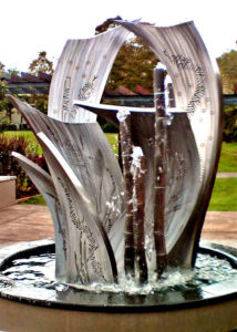 “Shields for Reconciliation” Stainless Steel water feature, 2.3m Shield artwork laser cut, Digeridoo art work hand carved, All work with internal LED lighting, All 5 Digeridoos charge with water, Kings School, Sydney